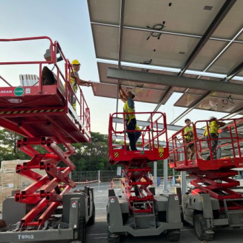 Workers on cranes installing photovoltaic panels