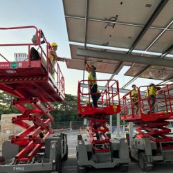 Trabajadores sobre grúas instalando placas fotovoltaicas