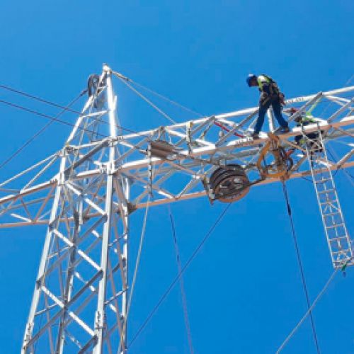 Worker on electrical tower doing the assembly